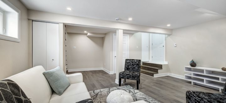 A sleek and modern basement living area featuring plush seating, clean lines, and neutral tones, ideal for relaxing or entertaining.
