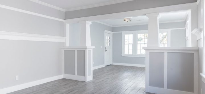 A spacious open-plan living space with light gray floors and white wainscoting, offering a versatile area for family gatherings or social events.