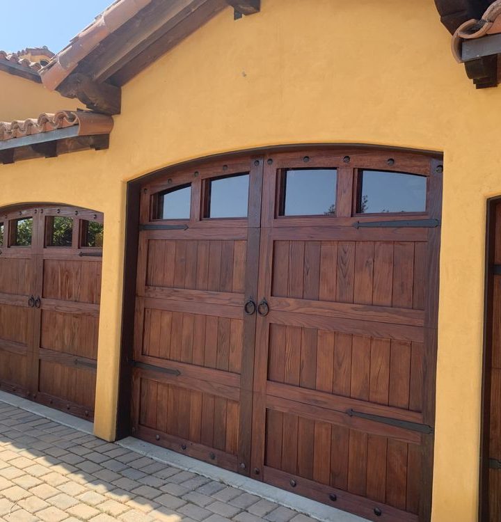 Ornate wooden garage doors of a Mediterranean-style house, showcasing the rich textures and craftsmanship in the design.