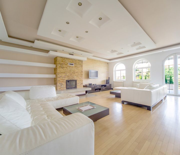 A spacious and luxurious living room featuring a natural stone accent wall, large arching windows, and plush furnishings, ideal for upscale living.