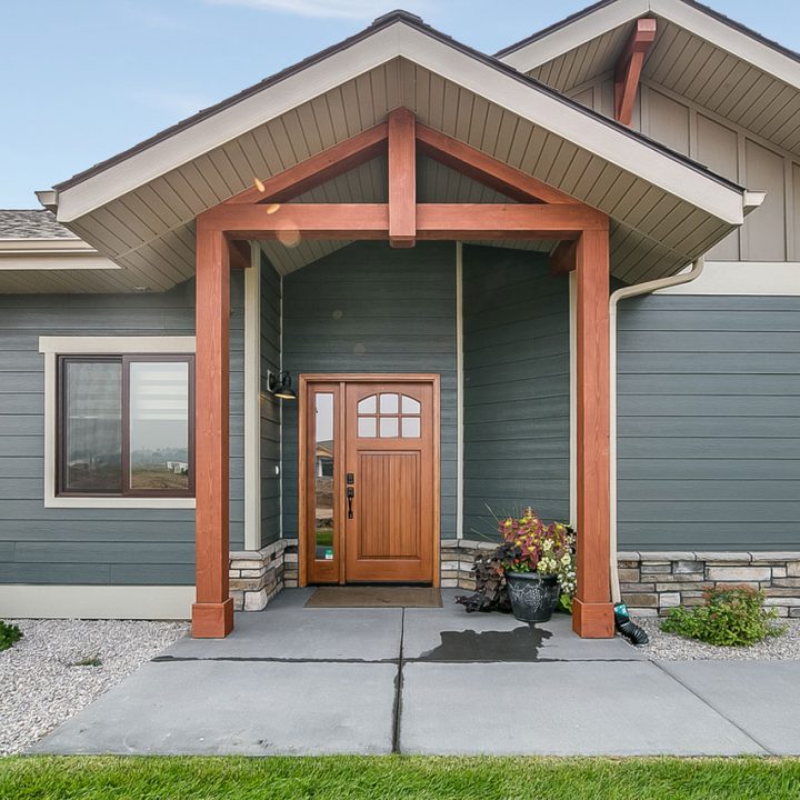 Elegant exterior of a modern home featuring a covered entryway with wooden posts and a stylish door, enhancing the home's curb appeal.