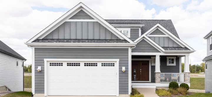A modern family home with gray siding, white trim, and a welcoming porch, showcasing contemporary architecture and curb appeal.